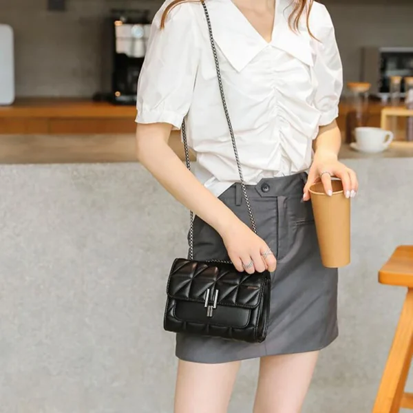 Woman holding coffee cup with black handbag.