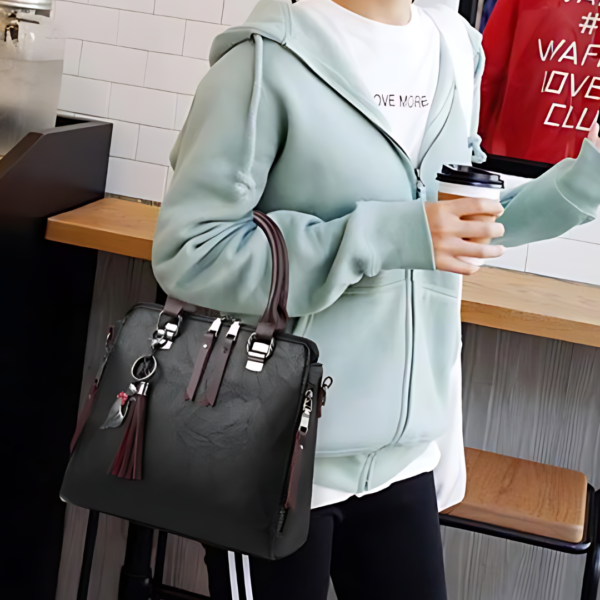 Person holding coffee cup with black handbag