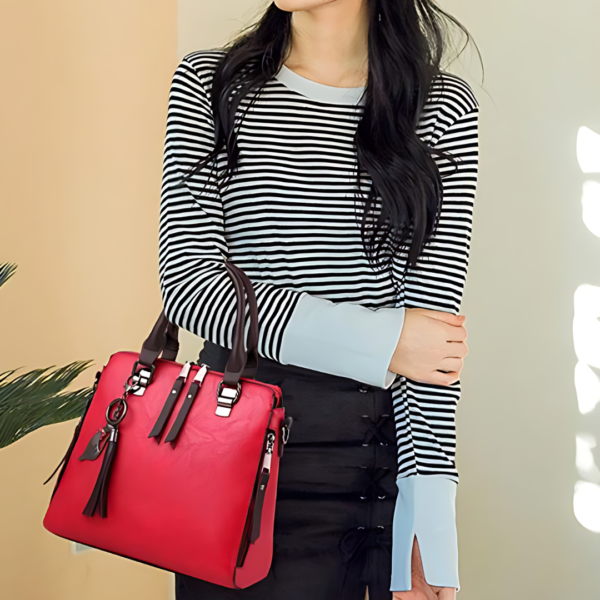 Person holding red handbag with black stripes shirt.