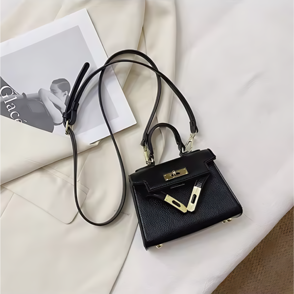 Black leather handbag with gold accents on a magazine.