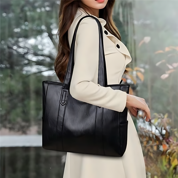 Woman in white coat with black handbag.