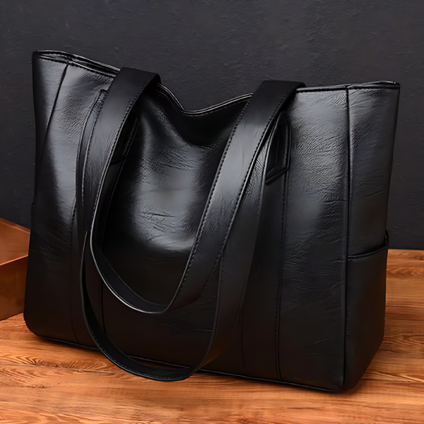 Black leather tote bag on wooden surface.